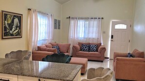 Un salón amplio con zona de cocina, un ventilador de techo y una puerta con ventanal.