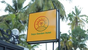 Letrero del Hotel Sayu Garden con un logo de sol y palmera.