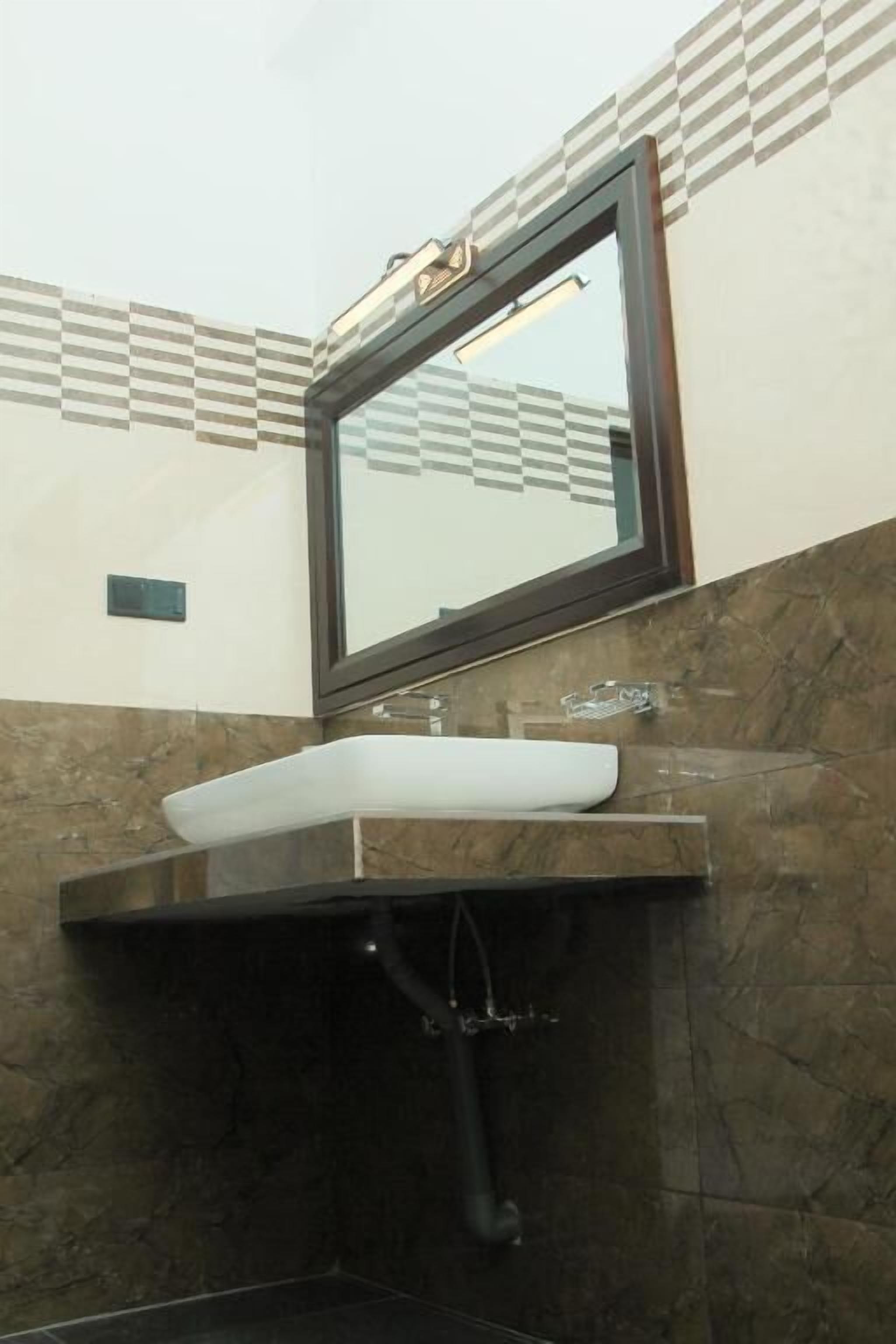 A bathroom with a white sink, a mirror, and a tiled wall.