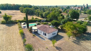 Una casa con piscina, circondata da alberi e un campo arido.