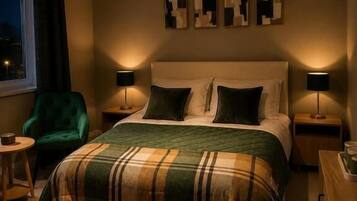 Ein Schlafzimmer mit einem Bett, zwei Nachttischen, einem grünen Sessel und einem Kunstwerk an der Wand.