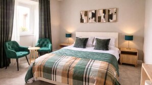 A bedroom with a bed, two nightstands, a bedside table, a chair, and a window with curtains. - The Station House Boutique Hotel (Burghead)
