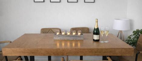 Een eettafel met champagne, glazen en kaarsen.