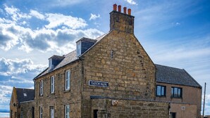 A stone building with a sign reading 'Station Hotel,' featuring a traditional architectural style with multiple windows and a chimney. - The Station House Boutique Hotel (Burghead)