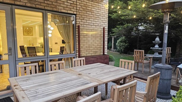 A patio with wooden tables and chairs, a brick wall, and a garden with a fountain. - Minutes from tube, exclusive central london location. Huge garden and spacious (London)