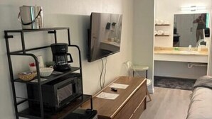 A compact hotel room with a kitchenette, a bed, a TV, and a mirror. - King Suite #18 at Glory Dayz (Eureka Springs)