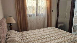 Ein Schlafzimmer mit Bett, Vorhängen, einer Lampe und einer Tür.