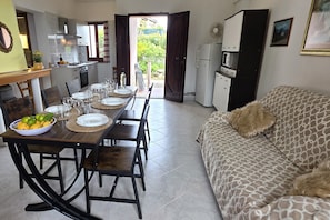 A dining area with a table set for four, a sofa, a kitchen with a refrigerator, and a view of the outdoors. - Two doubles with beautiful sea views in Costa Rei (Costa Rei)