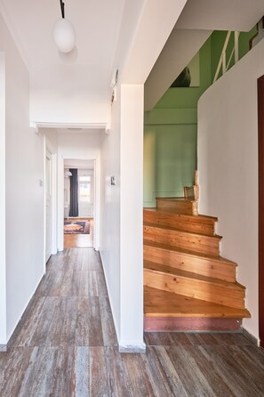 Ein Flur mit Holzboden, einer Treppe mit grünen Wänden und einer weißen Deckenleuchte.