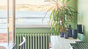 Een kamer met uitzicht op zee, een radiator, een plant en een tafel met speakers.