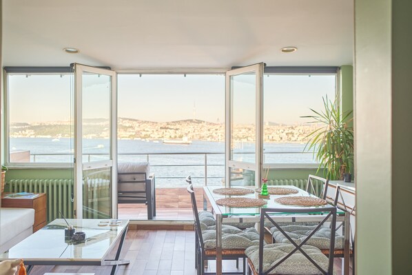 Ein Balkon mit Meerblick, einem Esstisch mit Stühlen und einer Couch.