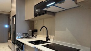 A modern kitchen with a built-in dishwasher, a stove, a sink, and a black range hood. - 301 Tara-jre Jabal Al Lweibdeh With Stunning View (Amman)