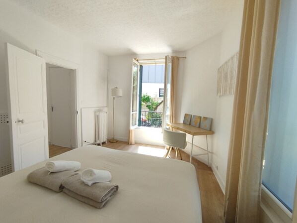 Ein Schlafzimmer mit Bett, Schreibtisch, Heizkörper und Blick ins Freie.