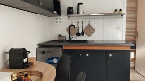 Eine kompakte Küche mit eingebautem Herd, einer Kaffeemaschine und einem Wasserkocher auf der Arbeitsfläche.