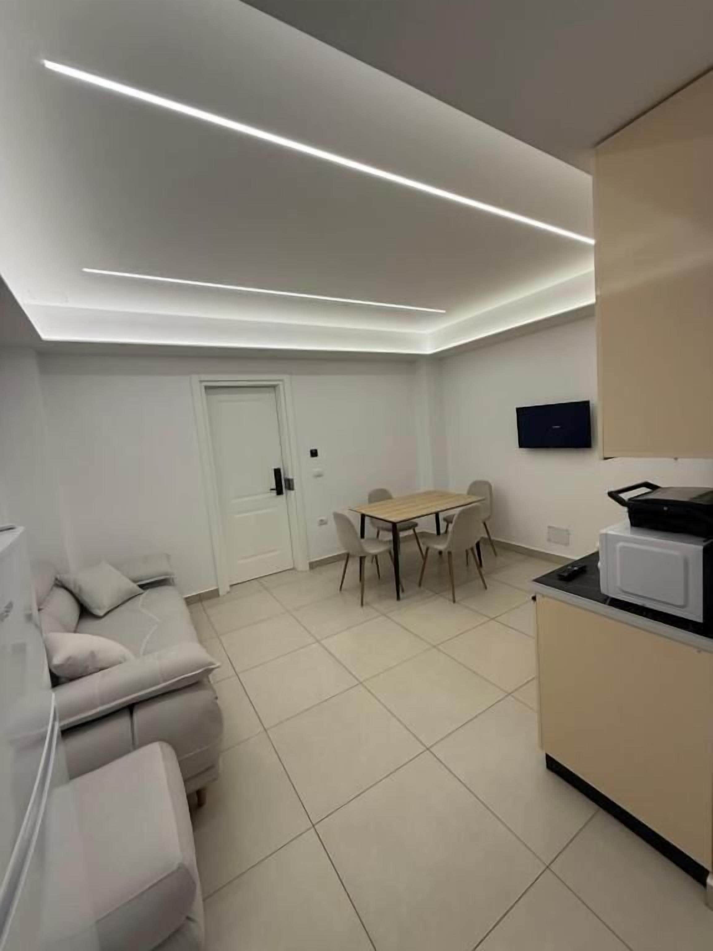 A modern kitchen with a dining area, a sofa, and a door.