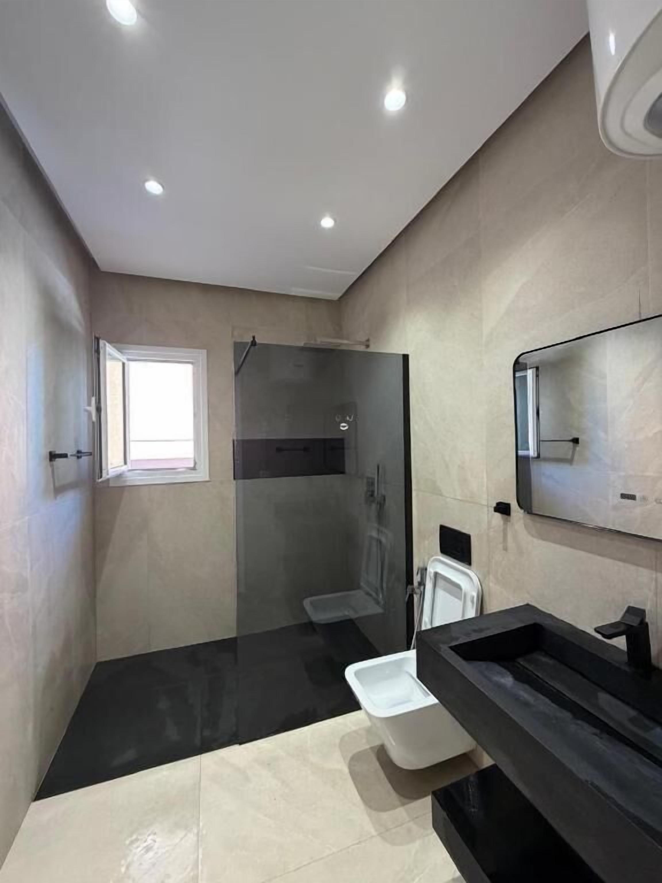 Un baño moderno con cabina de ducha de vidrio, un lavabo blanco y un espejo grande.