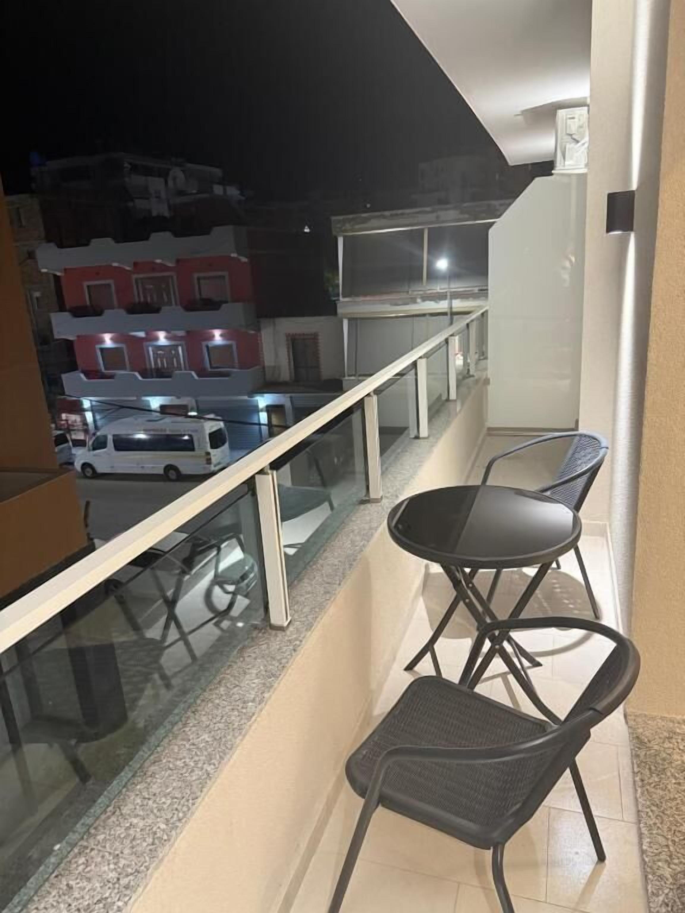 Un balcon doté d’une balustrade en verre, de deux chaises et d’une table.