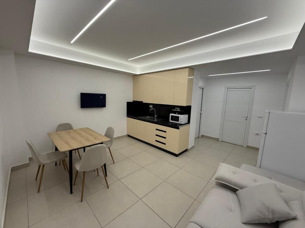 A modern kitchen with a microwave, a dining table with chairs, and a sofa in a living area.