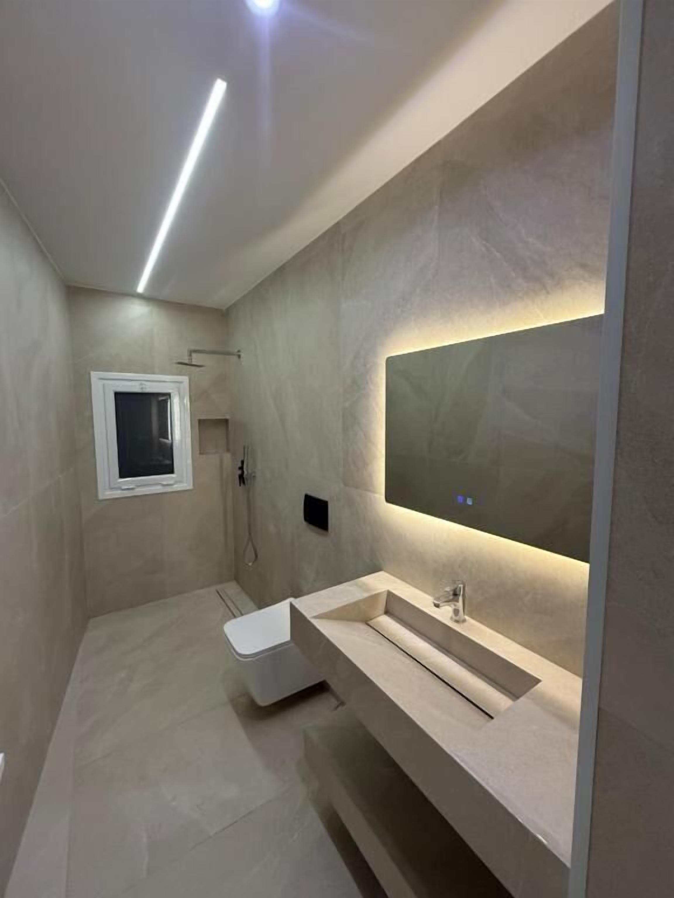 Uma casa de banho moderna com um espelho grande, uma pia e um chuveiro.