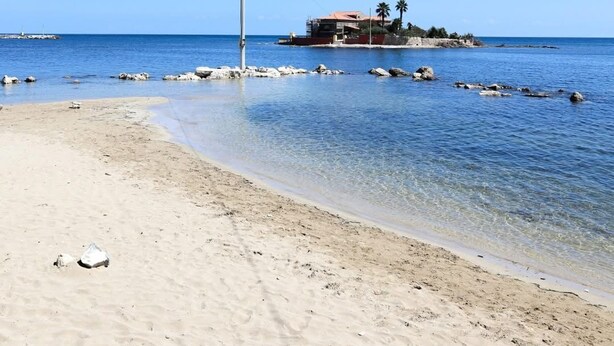 A beach with clear water, a sandy shore, and a building with a red roof. - Villino Marzamemi (Marzamemi)