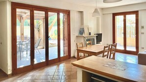 A spacious dining area with a wooden table and chairs, a TV, and a fireplace. - Villino Marzamemi (Marzamemi)