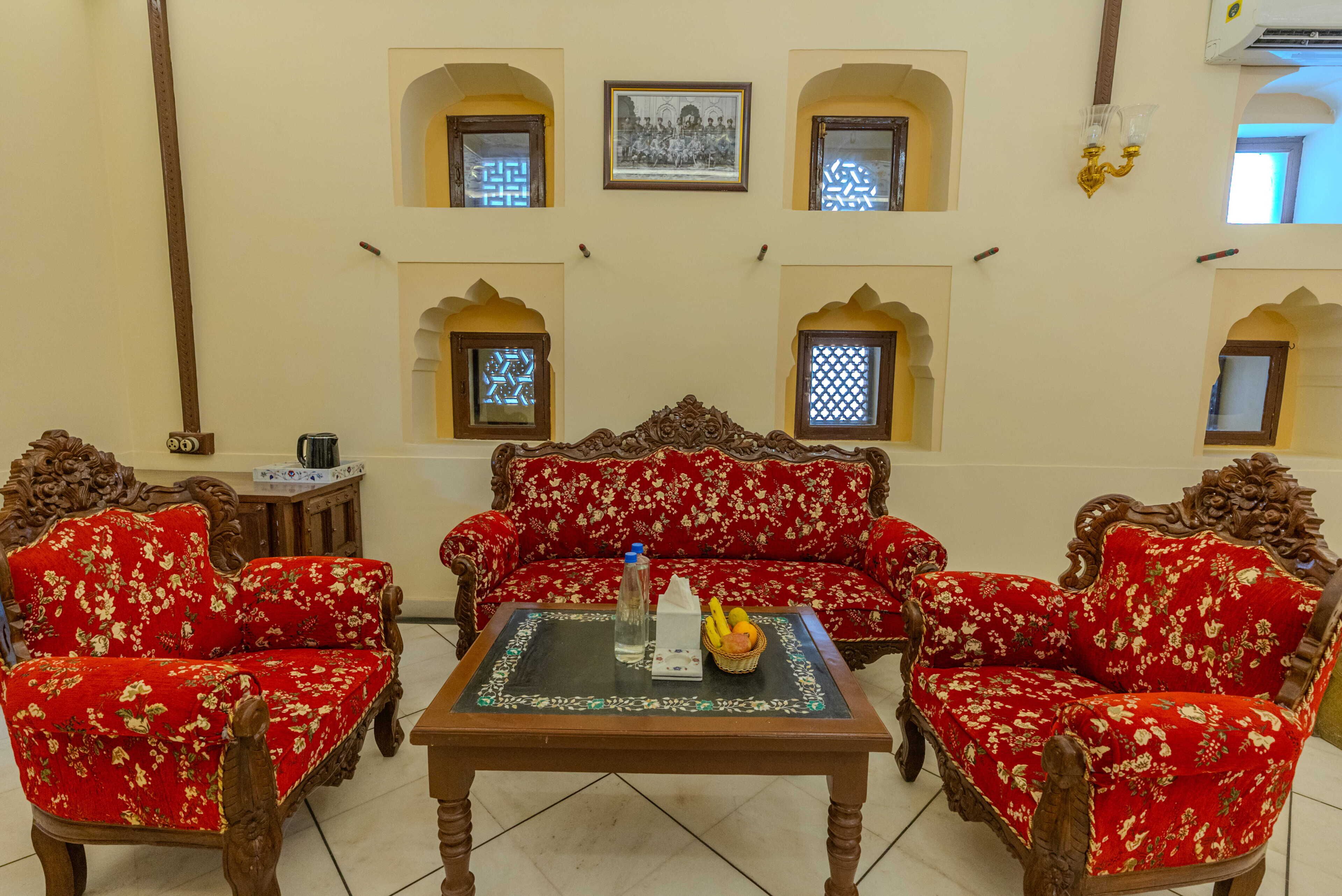 Una habitación tradicional con un conjunto de sofá, una mesa con una botella y fruta, y paneles decorativos en la pared.