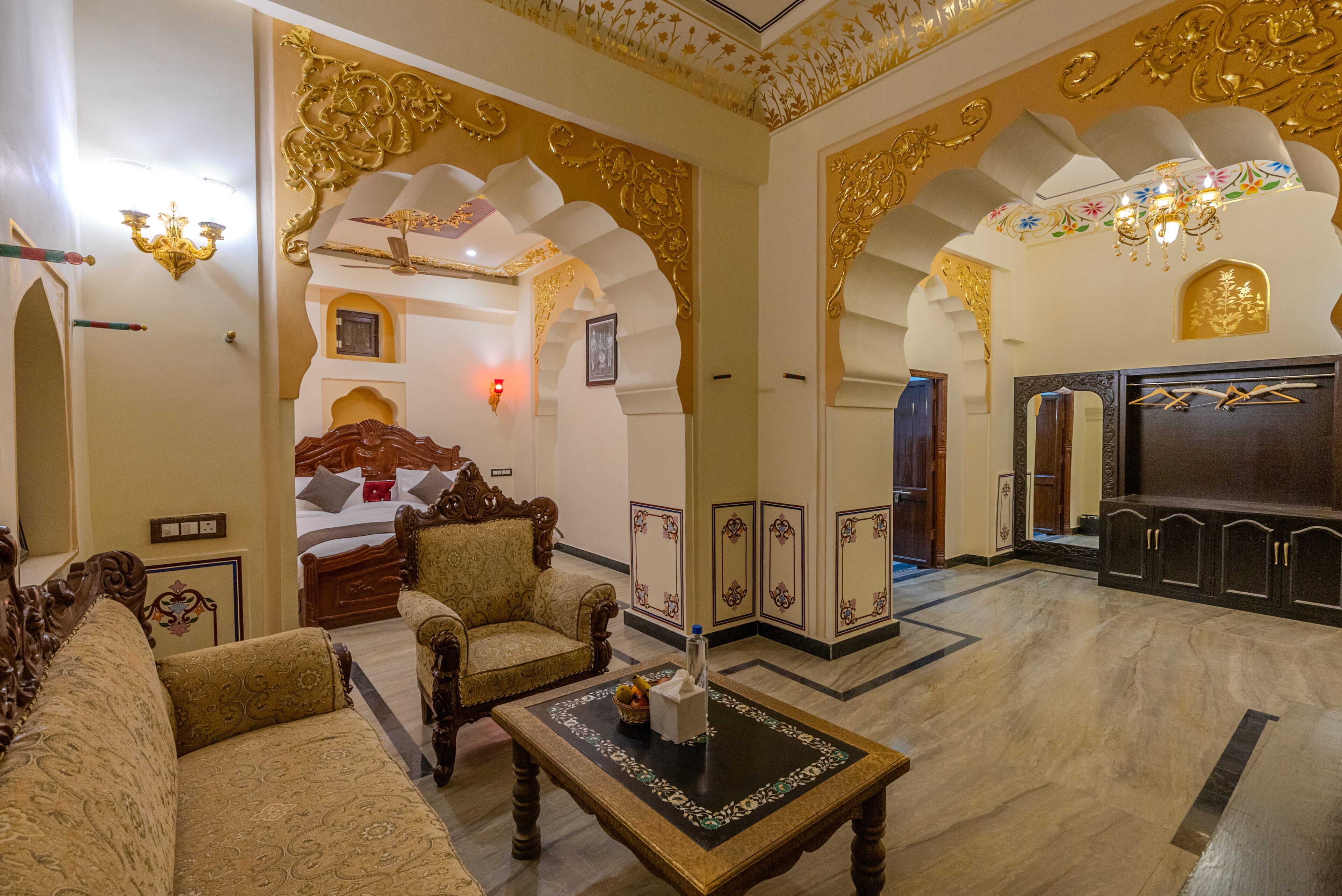 A traditional room with ornate decor, a bed, seating area, and a mirror.