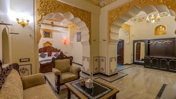 Una habitación tradicional con decoración elaborada, una cama, zona de estar y un espejo.
