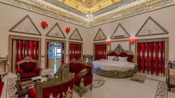 Une chambre à coucher luxueuse, dotée d’une décoration raffinée, d’un grand lit et de meubles recouverts d’un tissu rouge.
