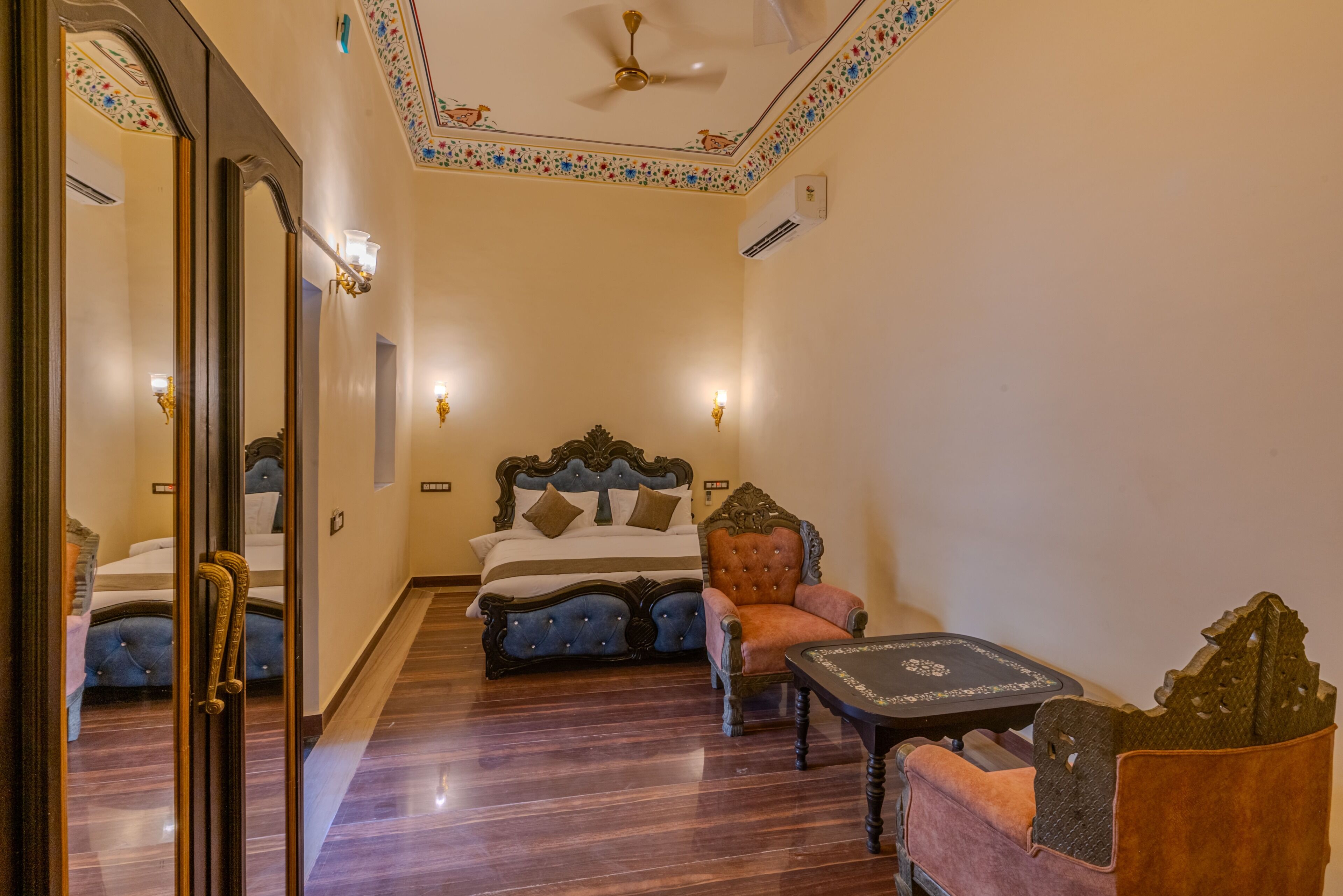 Una habitación de hotel con cama, una silla, una mesa y un espejo.