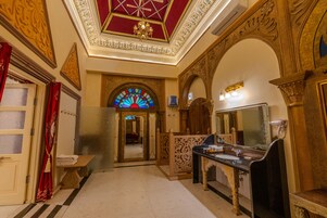 A luxurious hotel room with a large mirror, a vanity with a sink, and a decorative ceiling.