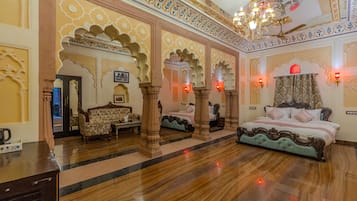 A luxurious bedroom with ornate arches, a chandelier, and a large bed with a patterned bedspread.
