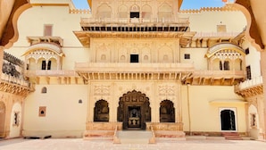 A grand entrance with intricate arches and a central doorway, leading to a spacious courtyard with patterned flooring.
