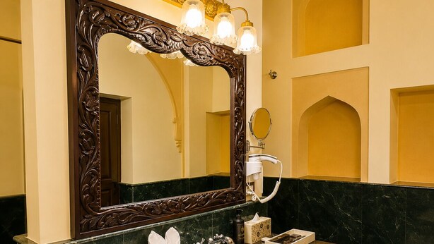A bathroom with a marble sink, a large ornate mirror, and a hairdryer.