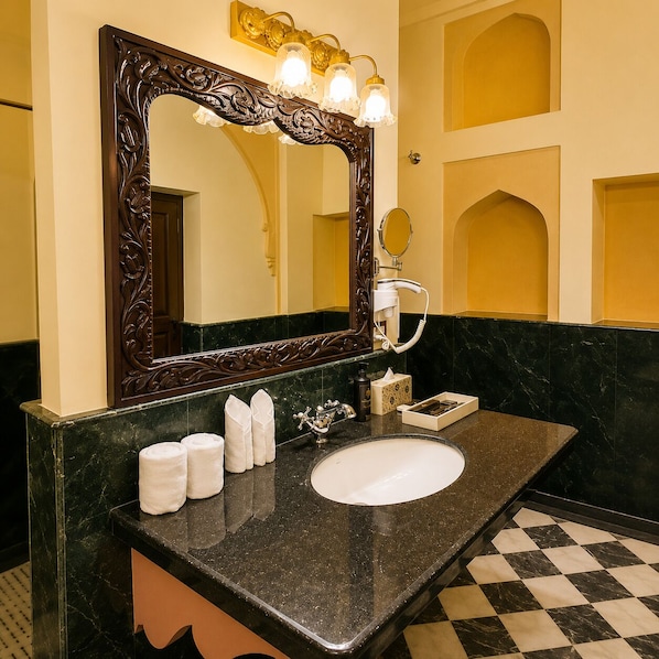 Une salle de bain avec un lavabo en marbre, un grand miroir décoratif et un sèche-cheveux.