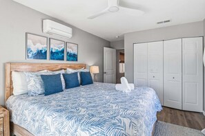 A bedroom with a bed, a ceiling fan, an air conditioning unit, and a wardrobe. - Sea Salt & Sunny Days: Pool, Spa, Putting Green by Anna Maria Life Vacation Rentals (Holmes Beach)