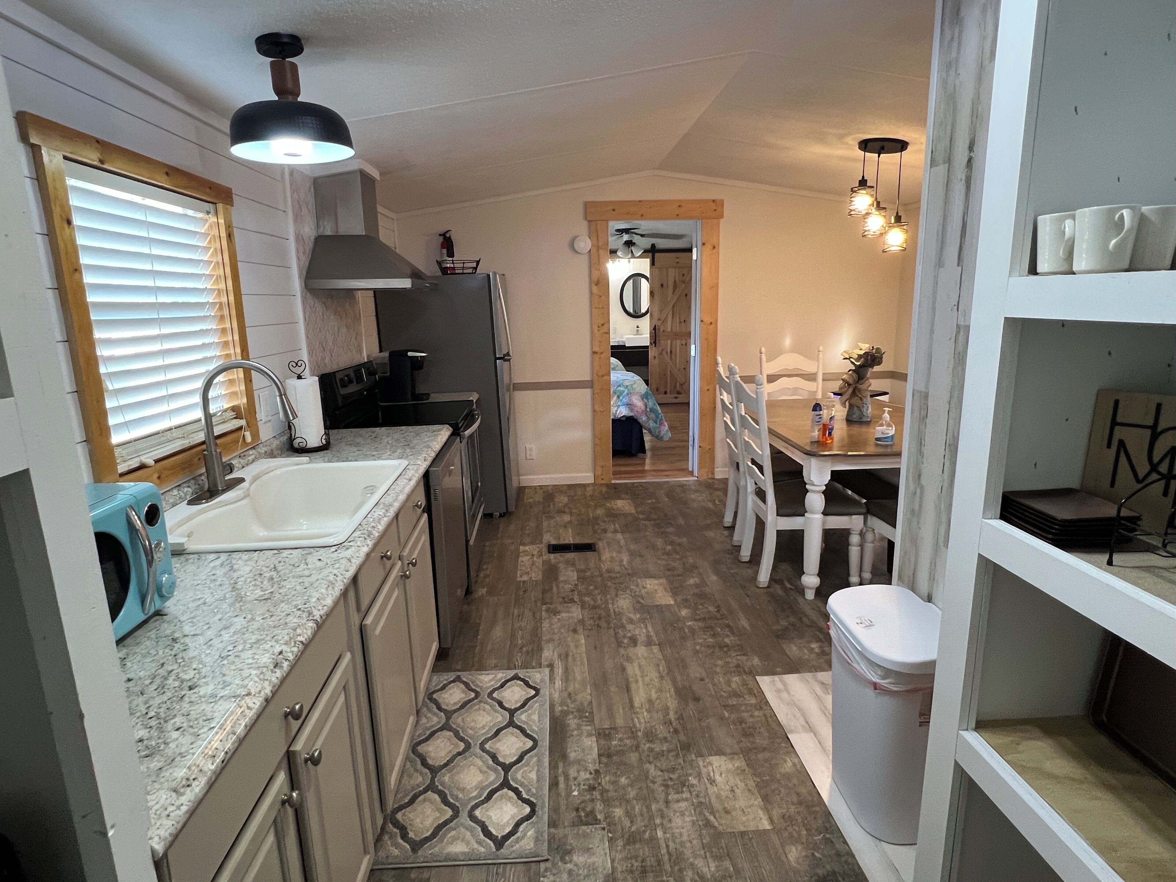 A compact kitchen with a sink, stove, and refrigerator. There is a dining area with a table and chairs.