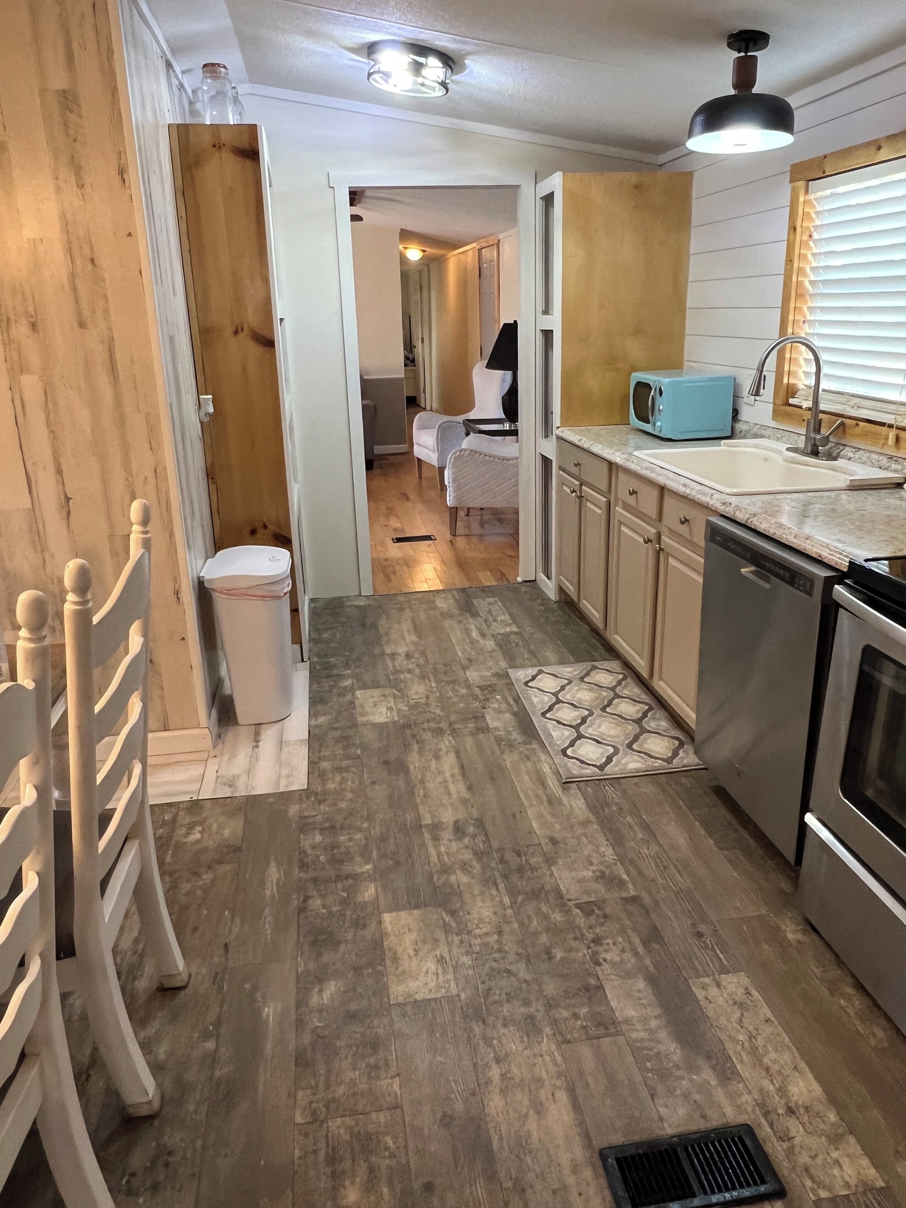 A compact kitchen with a dishwasher, stove, and a microwave on the countertop.