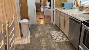 A compact kitchen with a dishwasher, stove, and a microwave on the countertop.