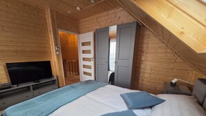 Ein Schlafzimmer mit Bett, Fernseher und einer Tür zu einem weiteren Raum.
