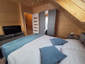 Ein Schlafzimmer mit Bett, Fernseher und einer Tür zu einem weiteren Raum.