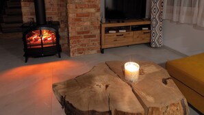 Ein Wohnzimmer mit Kamin aus Backsteinen, einem Fernseher und einem Couchtisch mit Kerze.