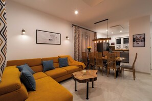 Ein modernes Wohnzimmer mit einer Couch, einem Esstisch, Stühlen und einem Couchtisch.