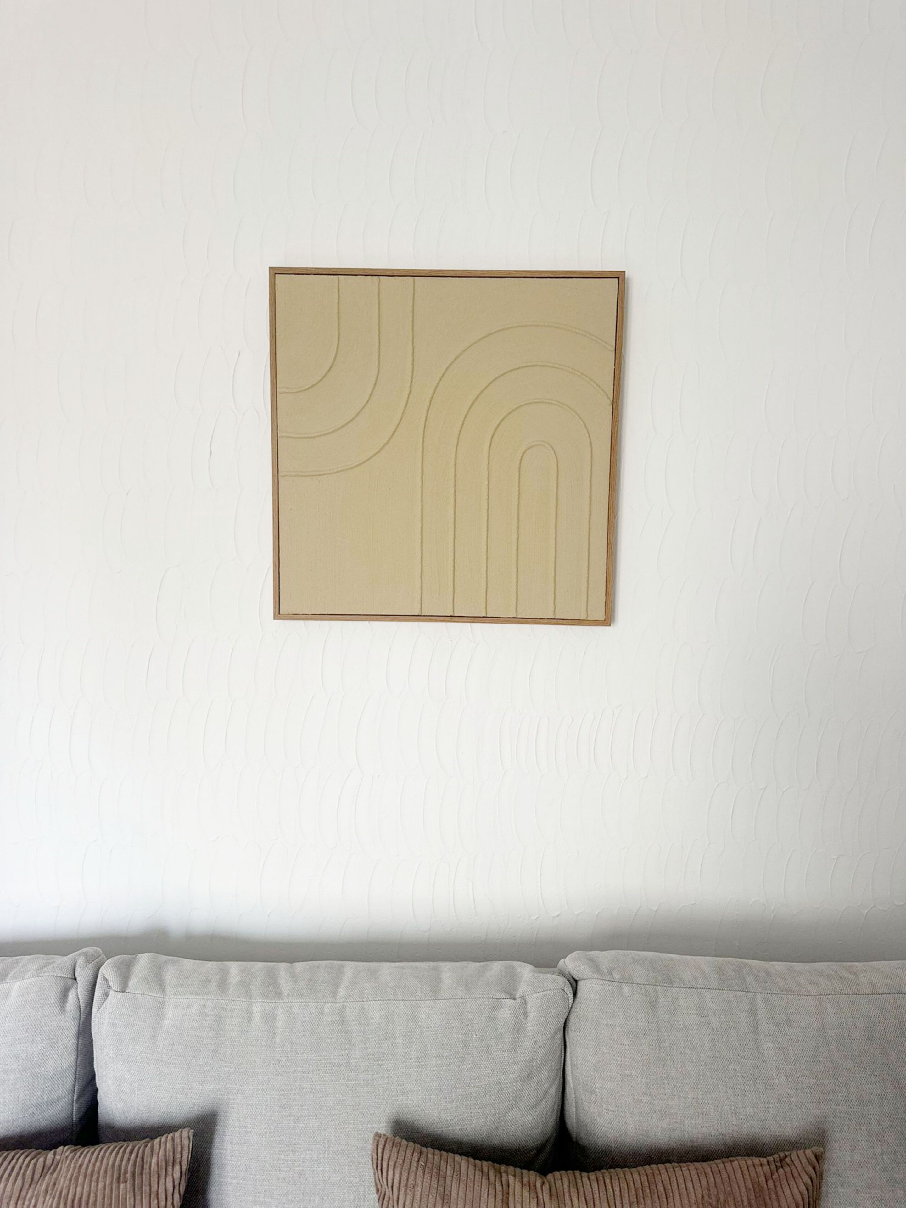 A wall with a textured pattern and a framed artwork.