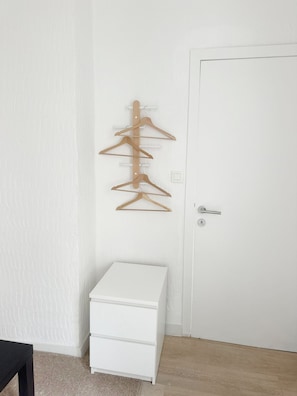 Un armario blanco con un perchero de madera encima.