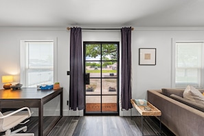 A room with a door leading to an outdoor area, a sofa, a table with a lamp, and a framed picture on the wall. - Bubbles bungalow Kerrville 3 bedroom (Kerrville)