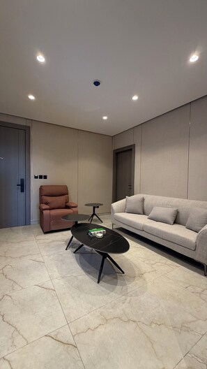 A modern living room with a sofa, a chair, a coffee table, recessed ceiling lights, and a door. - 302 Tara-jre Jabal Al Lweibdeh With Stunning View (Amman)
