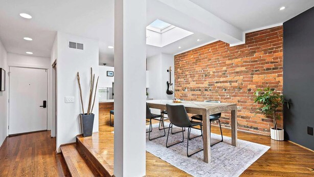 A modern interior with a dining area, wooden flooring, and a brick accent wall. - City View Perch Walkable Apt (Cincinnati)