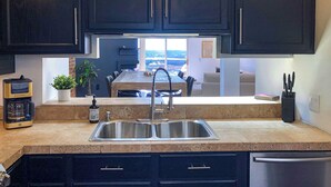 A modern kitchen with dark cabinetry, a stainless steel sink, and a coffee maker. - City View Perch Walkable Apt (Cincinnati)