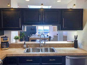 A modern kitchen with dark cabinetry, a stainless steel sink, and a coffee maker. - City View Perch Walkable Apt (Cincinnati)